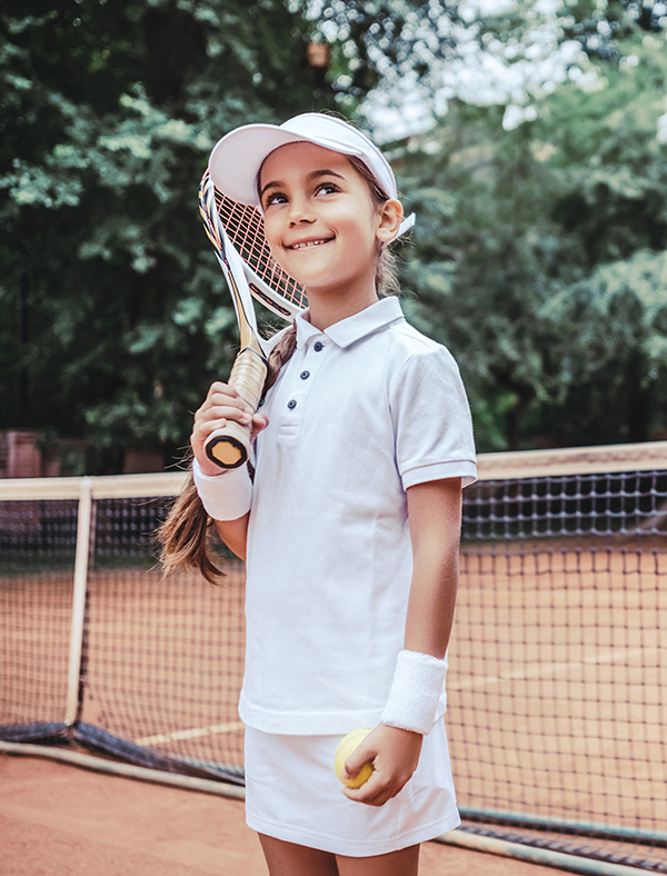 Little girl with tennis racket and ball in sport club. Active exercise for kids. Summer activities for children. Training for young kid. Child learning to play.